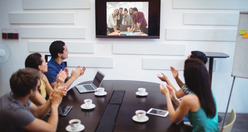 Business executives applauding during a video conference in the conference room